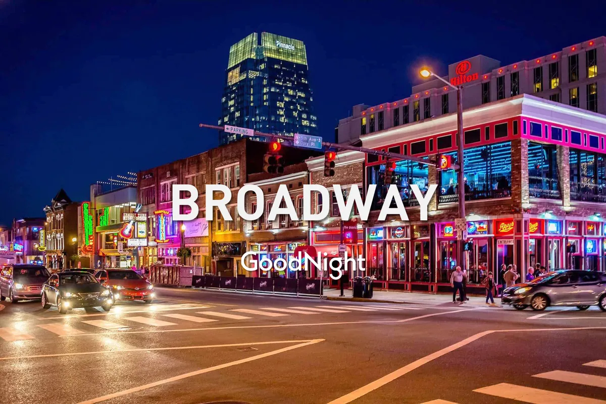 The image features neon-lit buildings, a busy street with people walking, and a festive urban atmosphere. The setting is unmistakably vibrant, with cues of nightlife, dining, and live music—key elements of Nashville's iconic entertainment scene.
