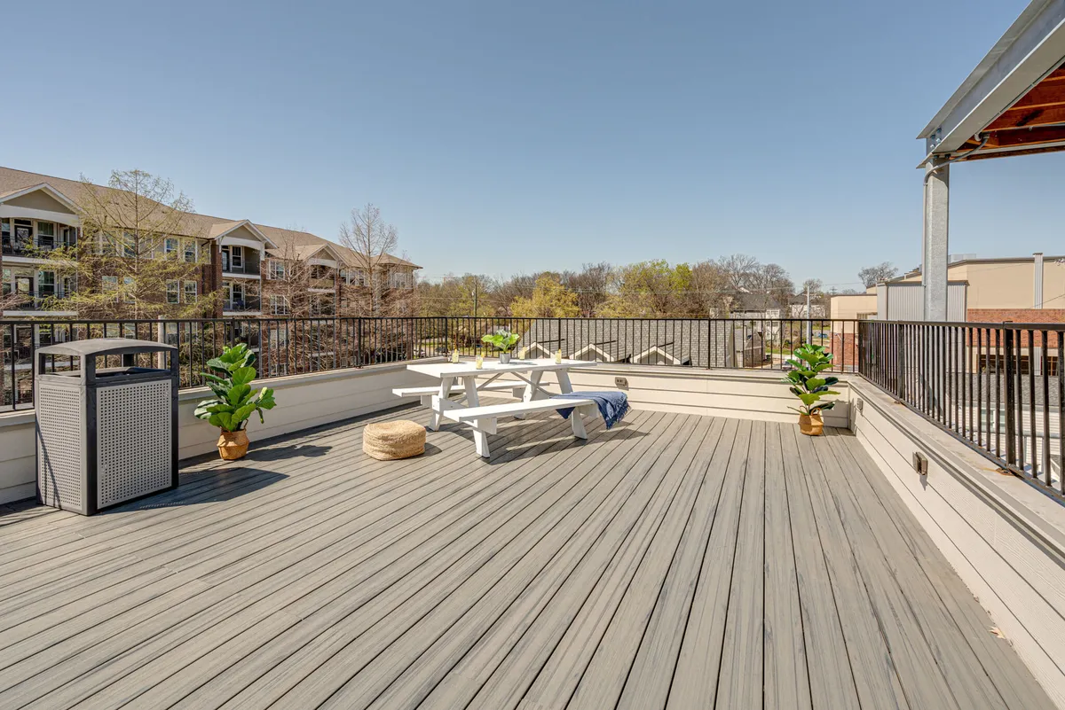 An exterior rooftop space with a picnic table, lush planters, and a view over the surrounding area. The scene suggests opportunities for outdoor dining, relaxing in the open air, and enjoying panoramic sunset or stargazing moments.