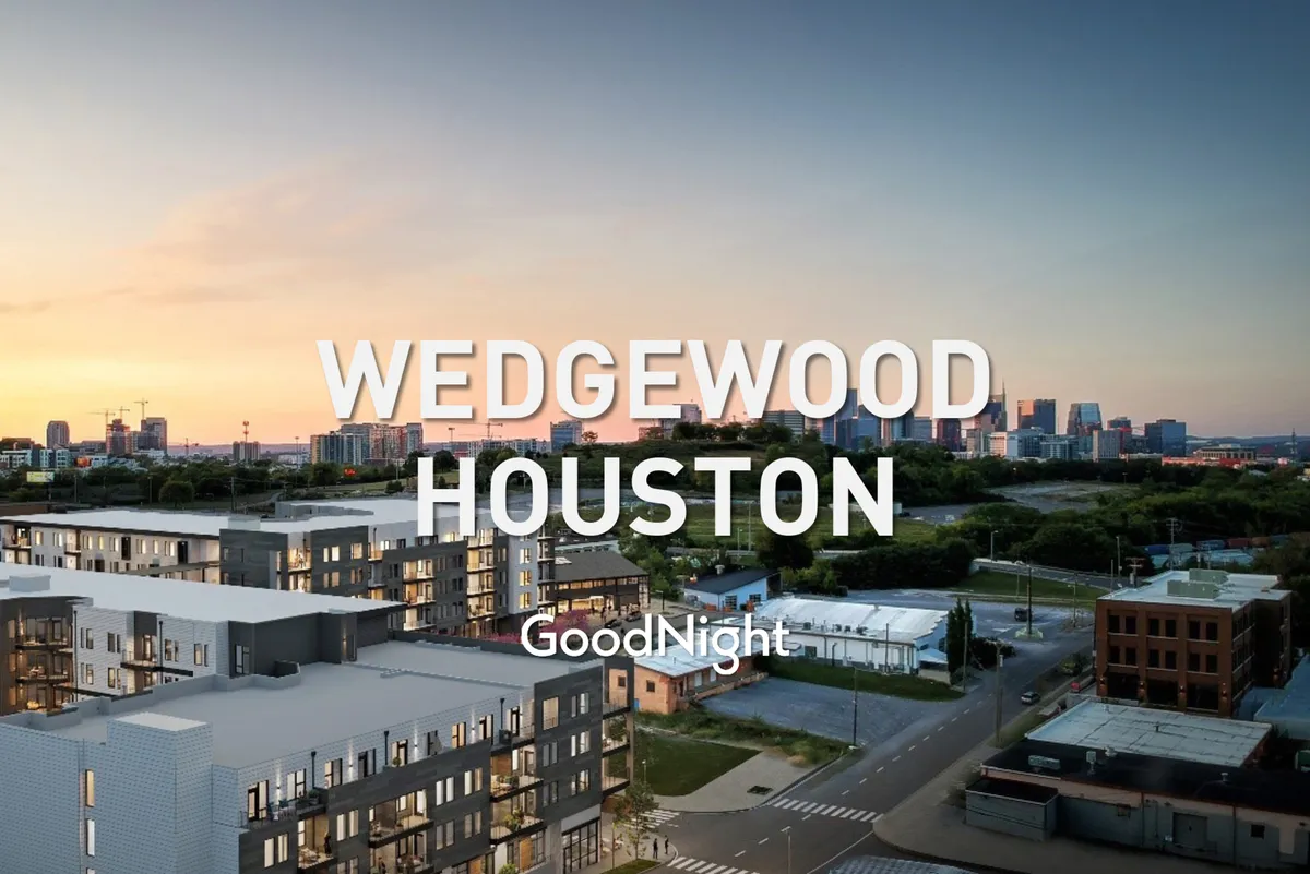 A vibrant exterior shot featuring modern apartment buildings with the Houston skyline in the distance and a dramatic sunset sky above. The rooftop is visible, hinting at communal spaces ideal for social gatherings and sunset viewing, while the overall scene conveys a sense of contemporary urban living.