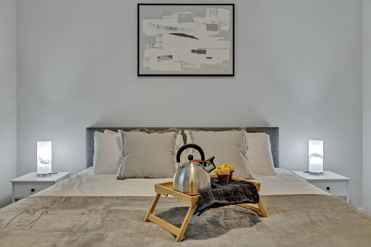 A well-appointed sleeping space with a comfortable bed, a tray with a kettle and snacks atop the duvet, and colorful artwork on the wall. The setting feels restful and versatile, ideal for additional guests or flexible sleeping arrangements.