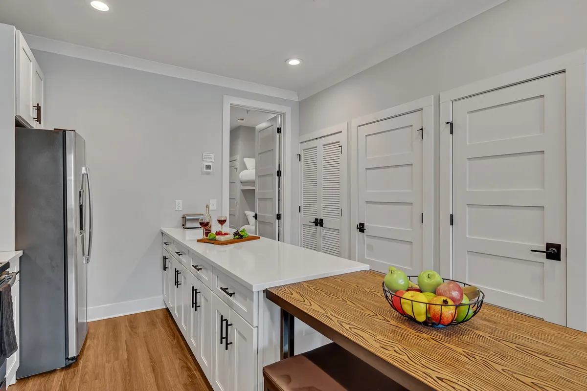 A kitchen/dining setup featuring an island countertop with a fruit bowl and a view of the adjacent dining area, ideal for casual conversations, morning coffees, or preparing meals together.